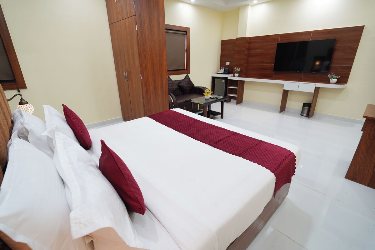 A hotel room with a bed, a desk, a TV, and a wardrobe.