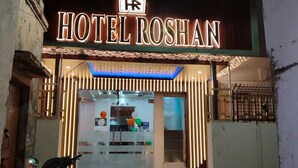 The exterior of Hotel Roshan with a neon sign, a glass facade, and a scooter parked in front. - HOTEL ROSHAN (Varanasi)