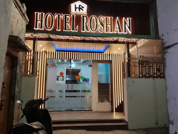 The exterior of Hotel Roshan with a neon sign, a glass facade, and a scooter parked in front. - HOTEL ROSHAN (Varanasi)