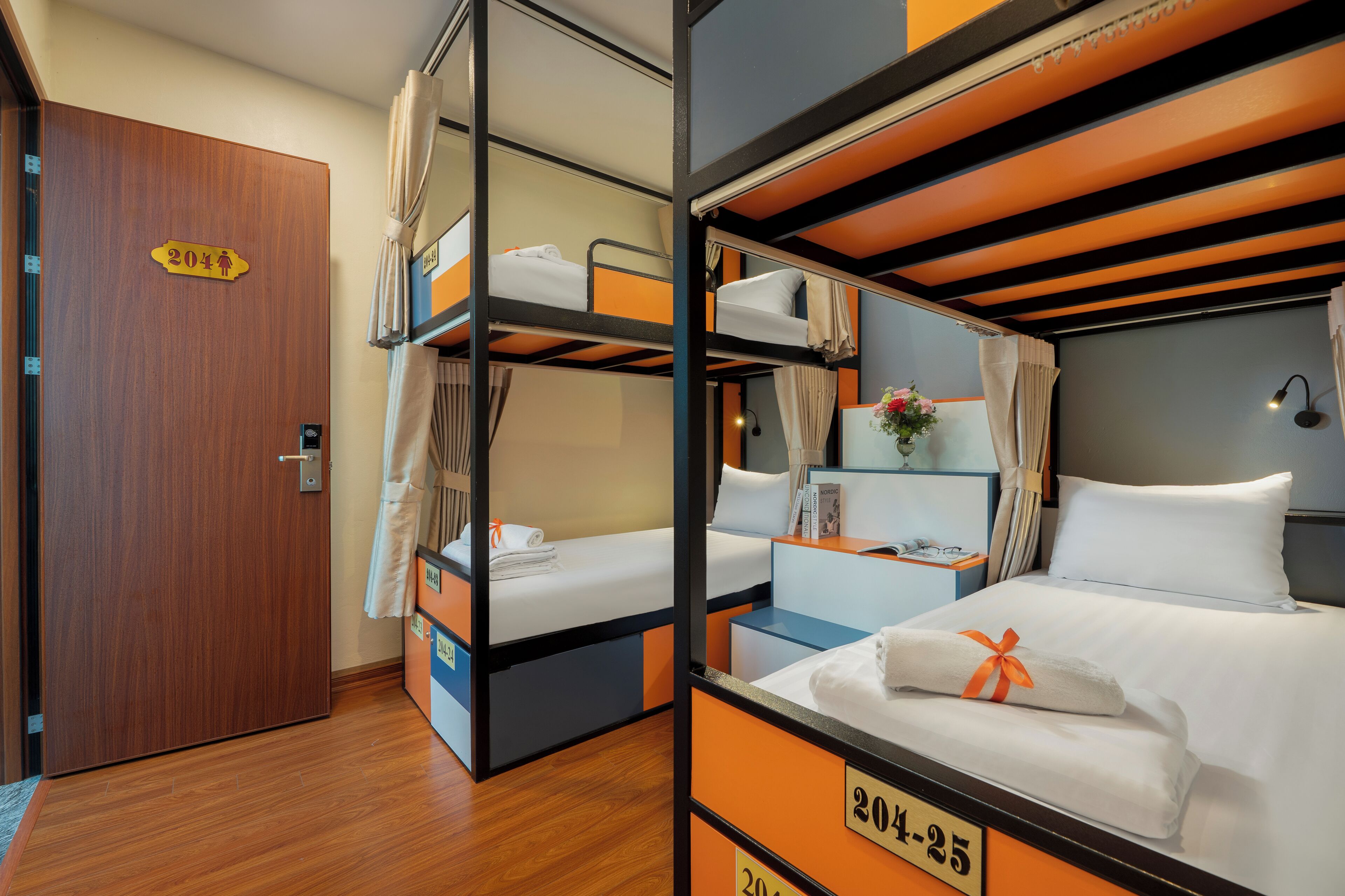 Ein Hotelzimmer mit Etagenbetten, einer Holztür und einem Schild mit der Zimmernummer 204-25.