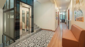 Corridoio d'albergo con pavimento decorato, zona reception e una scala che conduce a un altro piano.