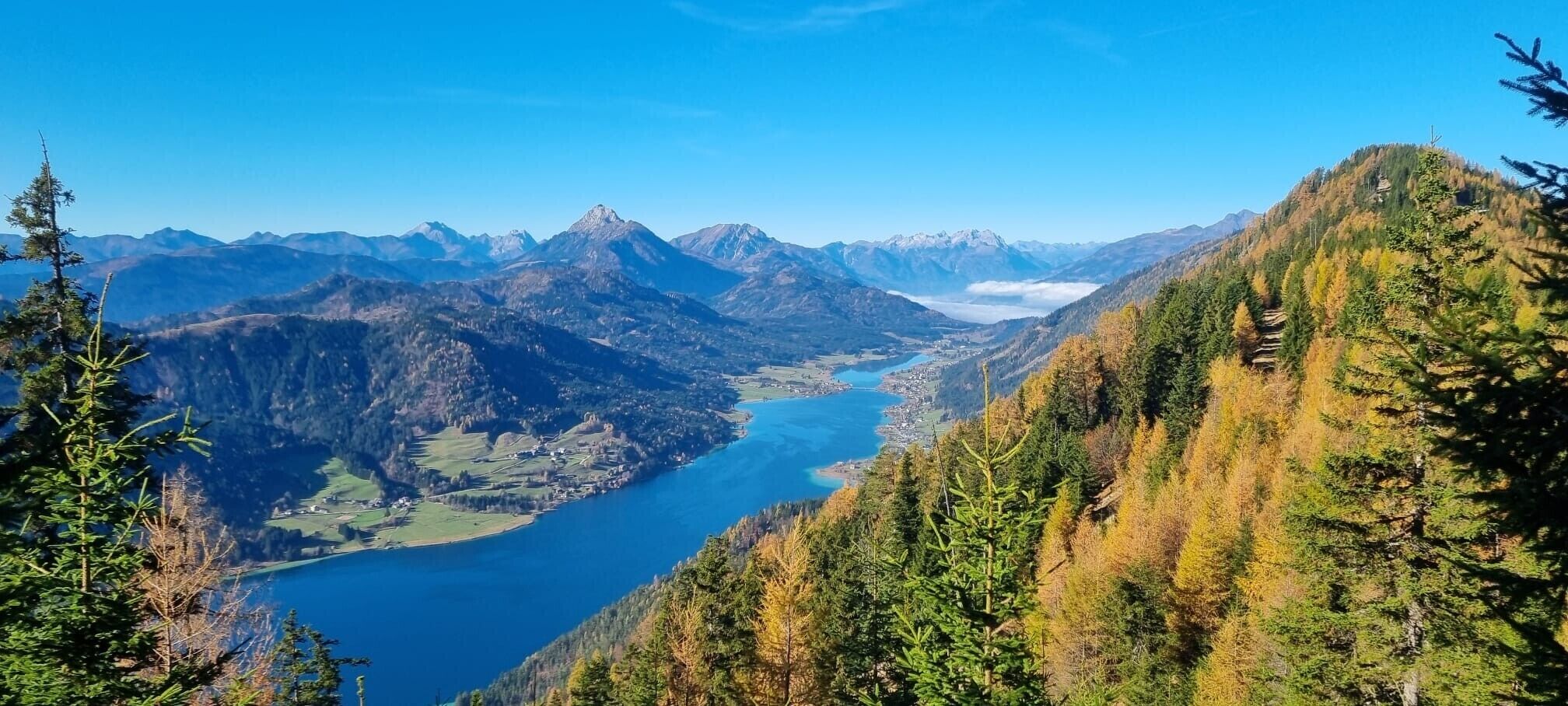 A mountainous landscape with a lake and forested areas.