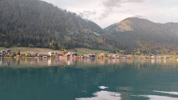 A lakeside village with houses along the shore, surrounded by forested hills.