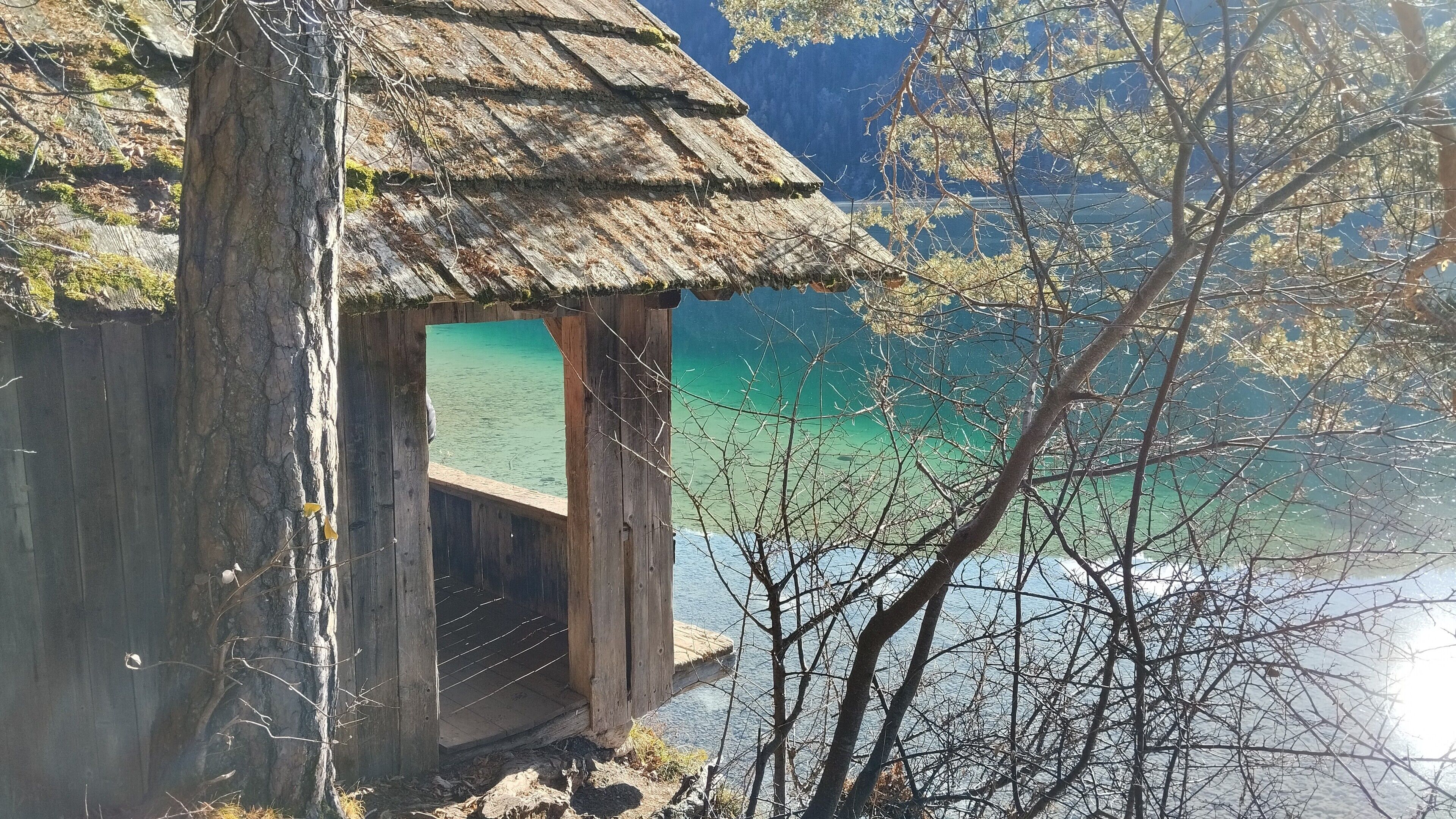 Una cabaña de madera con techo de paja que domina un lago turquesa.