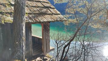 Una cabaña de madera con techo de paja que domina un lago turquesa.