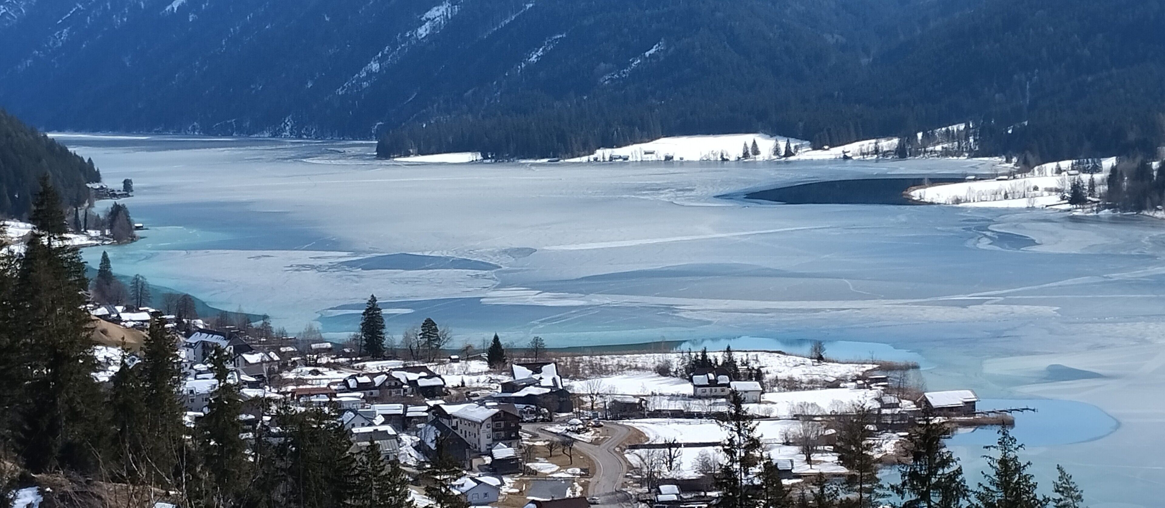 Un pueblo cubierto de nieve con edificios y un lago congelado.