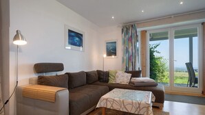 Ein modernes Wohnzimmer mit einer Couch, einem Couchtisch, einer Stehlampe und einem großen Fenster mit Blick.