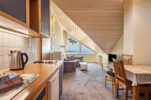 A kitchen with a wooden countertop, a kettle, and a dining area with a table and chairs.