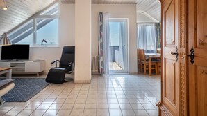 Una habitación moderna con televisión, una silla, una mesa y un armario.
