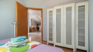 Un dormitorio con cama, armario y puerta que da a una cocina.