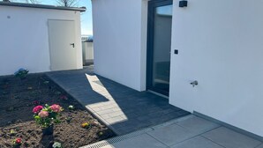 Un edificio moderno con tetto piatto, una porta e un piccolo giardino fiorito.