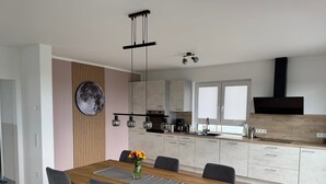 Una cucina moderna con un tavolo da pranzo in legno, sedie grigie e un lampadario.