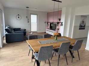 Un salon moderne comprenant un canapé, une table à manger, des chaises et un téléviseur.
