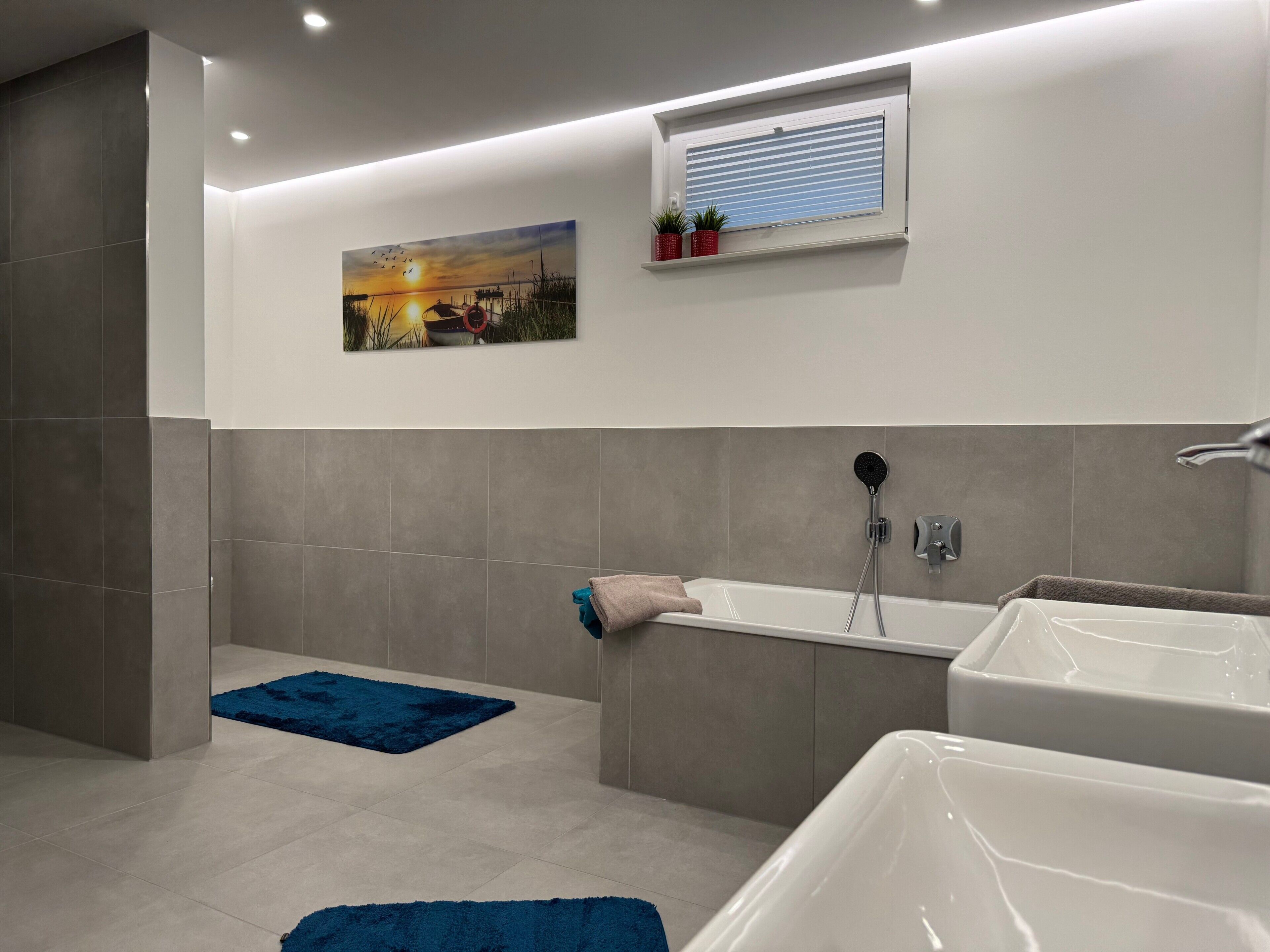 Een moderne badkamer met een bad, douche en een wandplank met planten.