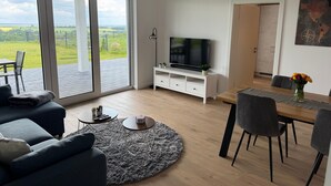 En moderne stue med sofa, sofabord, fjernsyn og spiseplads.