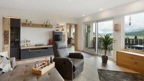 A modern living room with a sofa, a recliner, a wooden coffee table, and a potted plant.