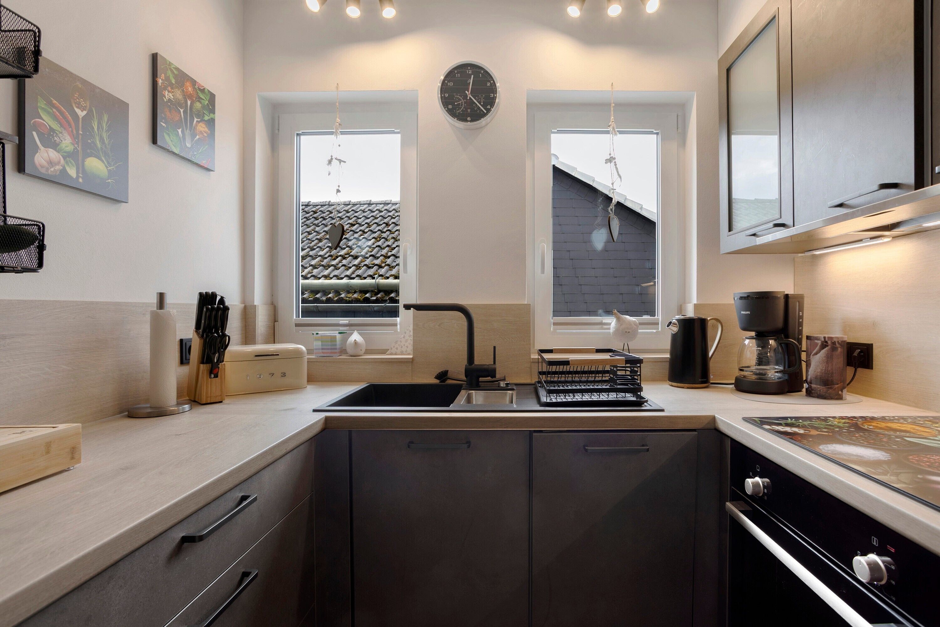 Een moderne keuken met een spoelbak, fornuis en een klok aan de muur.