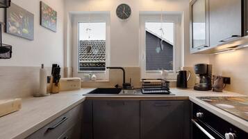 Een moderne keuken met een spoelbak, fornuis en een klok aan de muur.