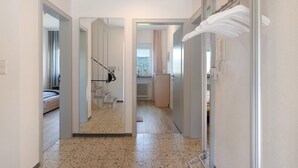 Un corridoio con un letto, uno specchio, un termosifone e una porta che dà su un bagno.