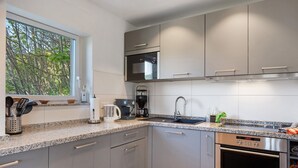 Una cucina moderna con una finestra, elettrodomestici in acciaio inossidabile e piani in granito.