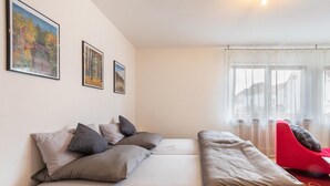 Ein modernes Zimmer mit einer Couch, einem roten Sessel und gerahmten Bildern an der Wand.