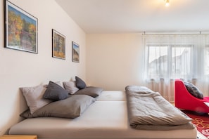 Ein modernes Zimmer mit einer Couch, einem roten Sessel und gerahmten Bildern an der Wand.