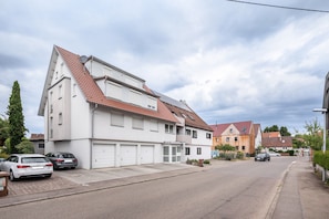 Eine Wohnstraße mit Häusern, parkenden Autos und blauem Himmel.