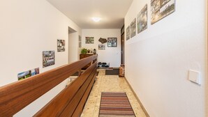 Ein Flur mit einer hölzernen Bank, einem Schuhregal und verschiedenen gerahmten Bildern an den Wänden.