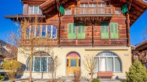 A traditional wooden house with a balcony, large windows, and a prominent entrance. - Lovely apartment for 4 guests with WIFI and balcony (Lenk)
