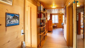A wooden interior with a hallway leading to a dining area, bookshelves, and framed pictures on the walls. - Lovely apartment for 4 guests with WIFI and balcony (Lenk)