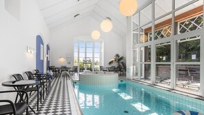 A pool area with a checkered floor, a hot tub, and tables and chairs for relaxation.