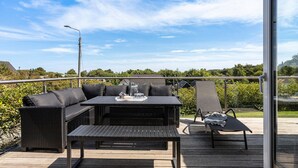 An outdoor patio with a dining table, chairs, and a lounge chair.