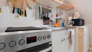 Una cocina con estufa, horno y varios utensilios colgando en la pared.