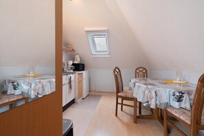Une petite cuisine avec une fenêtre, une table à manger avec des chaises et un four à micro-ondes.