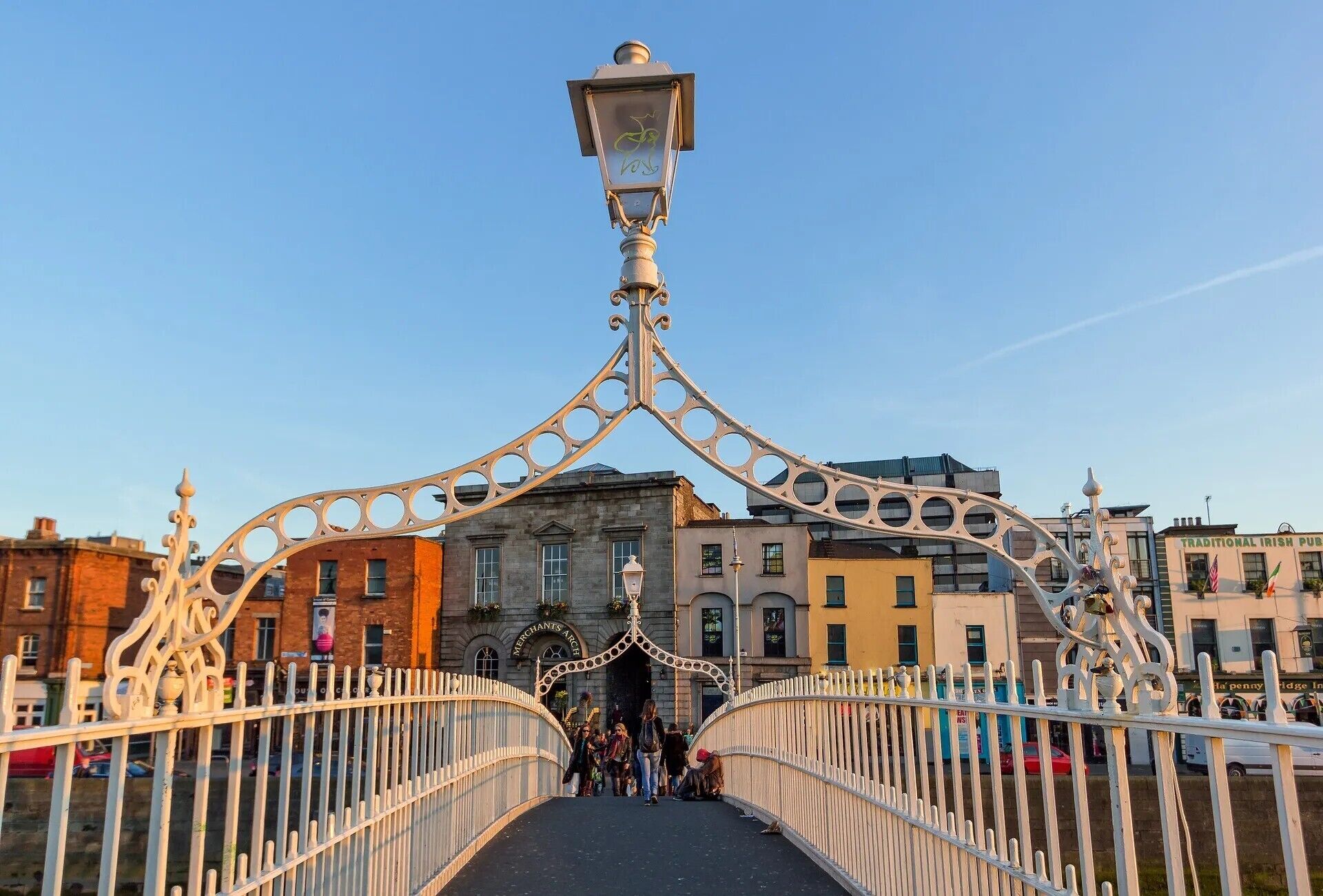 A pedestrian bridge with ornate metal railings and a street lamp.