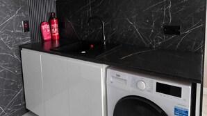 Una cocina compacta con lavadora, un lavamanos y armarios.