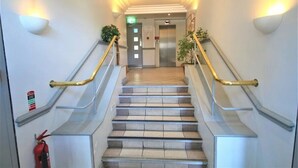 Un moderno vestíbulo de hotel con escalera, barandillas y extintor.