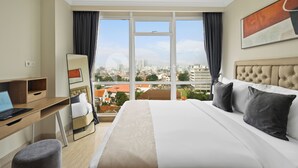 Ein Hotelzimmer mit Bett, Schreibtisch und Blick auf die Stadt.