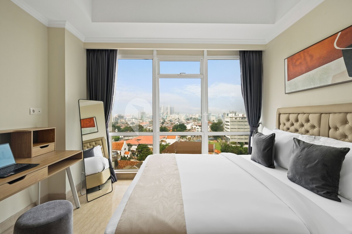 A hotel room with a bed, a desk, and a city view.