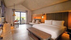 Ein modernes Hotelzimmer mit einem großen Bett, einem Essbereich und Blick ins Freie.