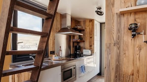 Een keuken met houten kasten, een roestvrijstalen afzuigkap, een inbouwoven en een raam met uitzicht op een mooi panorama.