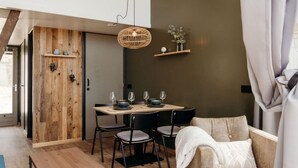 Een eethoek met een houten tafel, zwarte stoelen en een hanglamp.