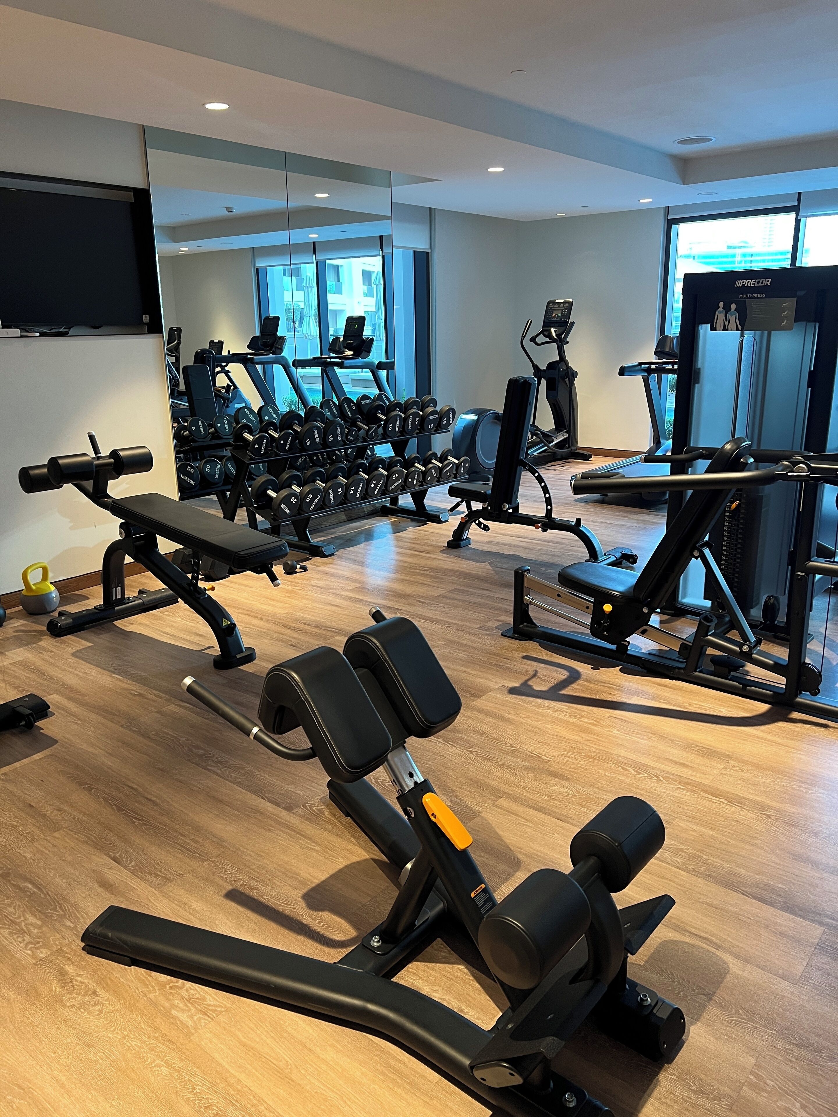 Ein Fitnessstudio mit Trainingsgeräten, einer Bank und einem Laufband.