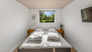 A bedroom with a large bed, two bedside tables, a window with a view of greenery, and a flat-screen TV mounted on the wall. - "Smilla" - 1.1km from the sea by Interhome (Hals)