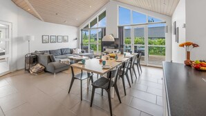 A spacious living area with a dining table, grey sofa, and large windows offering a view of the outdoors. - "Smilla" - 1.1km from the sea by Interhome (Hals)