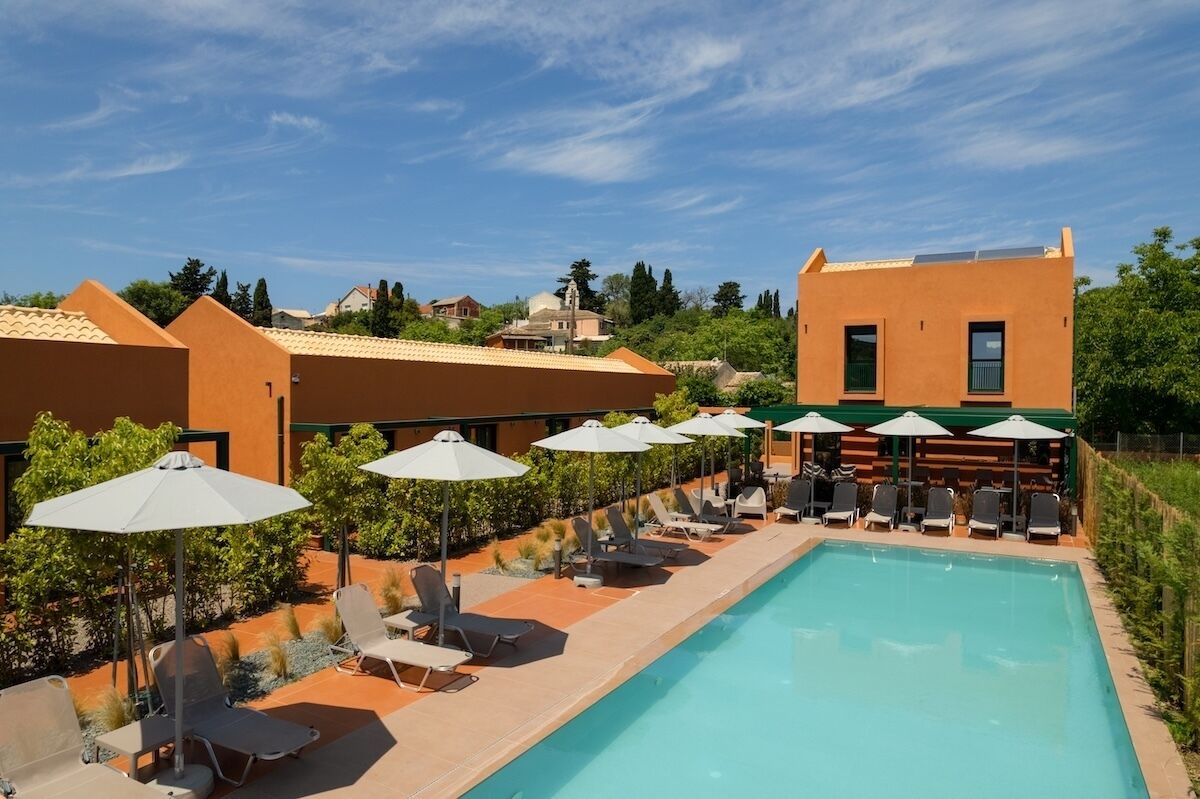 A poolside area with lounge chairs and umbrellas, a swimming pool, and a building with a modern design.