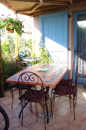 Un patio al aire libre con una mesa de baldosas y sillas de metal.