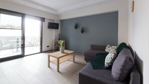 Ein modernes Wohnzimmer mit einer Couch, einem Couchtisch und einem an der Wand befestigten Fernseher.