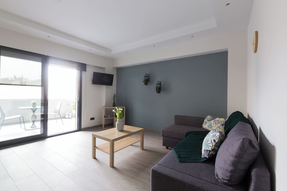 A modern living room with a sofa, a coffee table, and a TV mounted on the wall.