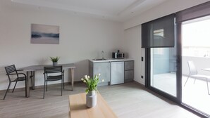 Eine moderne Küche mit Mikrowelle, Spüle und Schrank. Es gibt einen Essbereich mit Tisch und Stühlen, und auf dem Tisch steht ein Blumentopf.